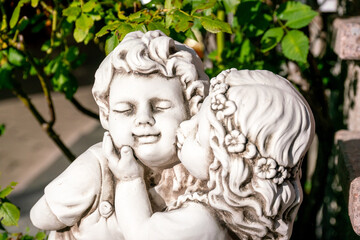 A statue of white stone. Monument to a girl kissing a boy on the cheek