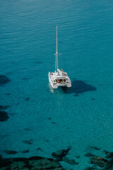Boat docked by the sea in Ibiza. Overlooking rocky island, houses, sunrise, calm sea