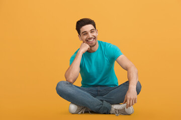 Young caucasian man on orange background in studio