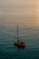 Fototapeta premium Boat docked by the sea in Ibiza. Overlooking rocky island, houses, sunrise, calm sea