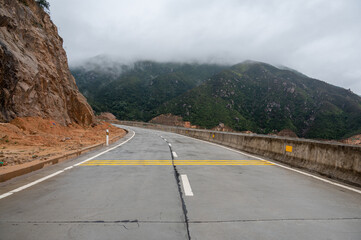 A road leading to the mountains. There is fog on the mountains