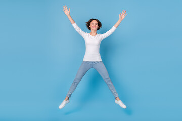Fototapeta na wymiar Full size photo of excited crazy cheerful girl jumping in star pose fooling around isolated on blue color background