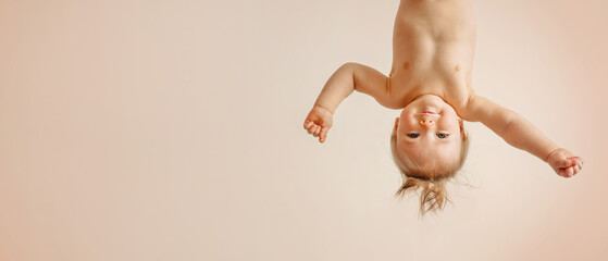 a kid with a funny forelock is hanging upside down and smiling, plain peach, light coral...