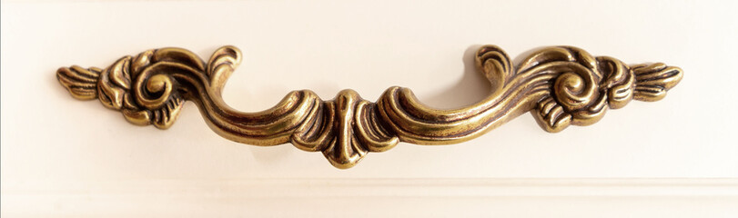 Copper furniture handle, on white wooden cabinet .