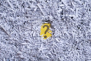 white shredded paper revealing a question mark. Concept of questions, secret and recycle