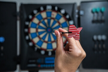 Woman hand aiming at dartboard bullseye with a red dart