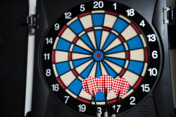 Picture of a three red darts with a dartboard in the background