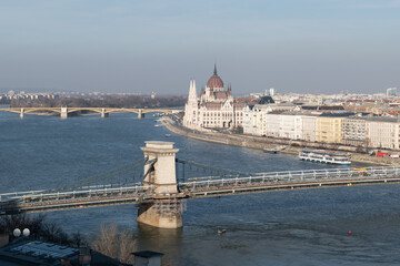 Fototapeta premium Szechenyi chain bridge across Danube river under renovation and parliament building in Budapest, Hungary