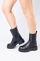 Women's black spring boots made of genuine leather are dressed on bare feet