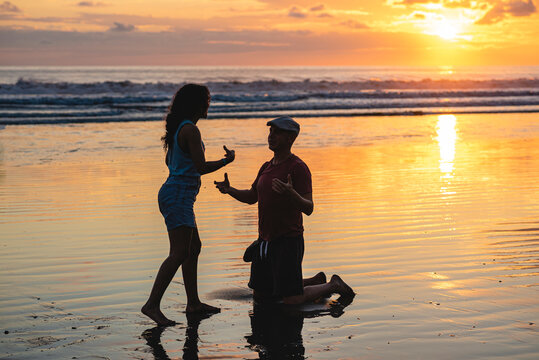man on the beach on his knees asking a woman to marry him in a beautiful Costa Rican sunset