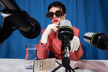 microphones near glass of water, dictaphone and vintage style woman on blue background