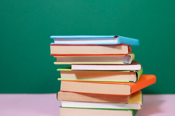 Composition with vintage old hardback books, diary, fanned pages on wooden deck table and colored background. Books stacking. Back to school. Copy Space. Education background.