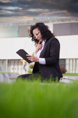 Female in a suit thinking and reading online news on her tablet