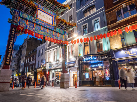 Dragon Gate, Chinatown, London. A dusk view of tourists passing through the landmark gate in the popular central London shopping and dining district.