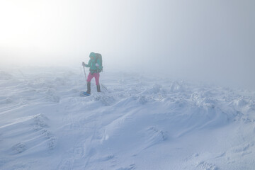 Fototapeta na wymiar A woman in the winter trekking during the fog