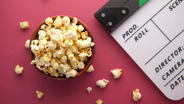 Movie clapper board and popcorn on red background 