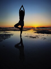 Silhouette of the yoga on the beach,posing in front of the sunset on the beach.