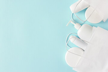 Cosmetic products in white paper merchandise bag on pastel blue background. Buying cosmetics. Beauty shopping and sale concept. Flat lay. Copy space