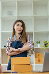 Starting a Small Business, SME, Independent Entrepreneur Asian woman working at home with cardboard boxes, smartphones, laptops, online, marketing, packaging, transportation, SME, e-commerce concept.
