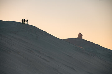 snow-covered mountain slope along the top of which a group of skiers is walking. Ski touring concept