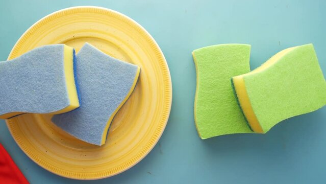 sponge , rubber gloves and colorful plate on pink 