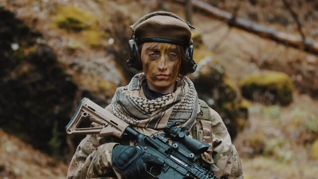 armed female soldier holding an automatic rifle portrait looking to the camera - army career concept. High quality 4k footage