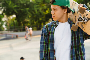 Hispanic boy holding skateboard while spending time at skate park