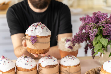 man holds close-up of an Easter cake in his hands. Traditional pastries for happy Easter. Strong men hands gently hold a festive cupcake decorated with flowers