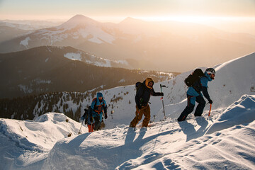 group of skiers climbing up at snow-covered mountain trail against the backdrop of a beautiful winter mountain landscape