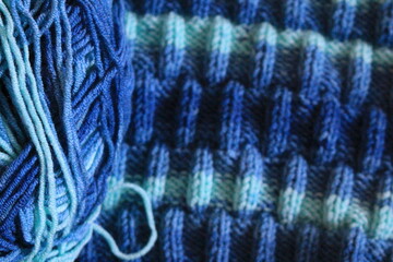 The canvas is knitted from melange yarn with knitting needles. The knit and purl stitches alternate in the pattern. Knitting is a hobby for many women.