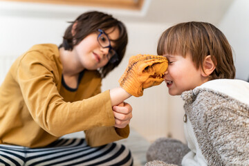 Big brother playing with a toddler sibling at home with a dinosaur , coming up with an interesting game. Good relationships between family members concept.