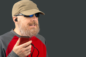 bearded man enjoys listening to his favorite music through an audio player in small headphones....