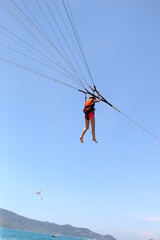 A woman is gliding using a parachute on the background of cloudy blue sky.