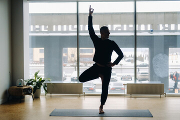 Fototapeta na wymiar A man in black sportswear is doing Yoga, stretching in the gym