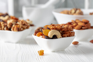Mix of nuts and raisins on a white wooden table.