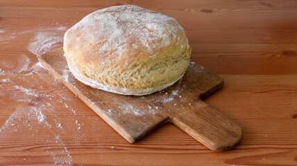loaf of rustic home made bread on a bread board with flour