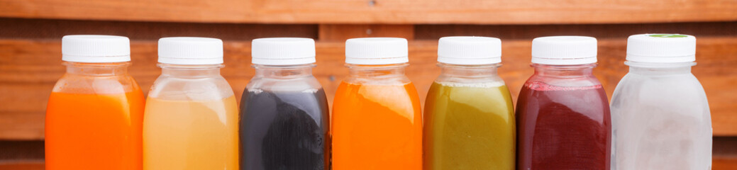 Many detox juice bottles on table over wooden background.