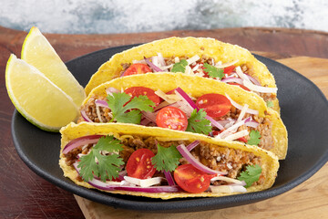 Focus on mexican tacos stuffed with minced beef, tomatoes, onion, cheese and coriander.