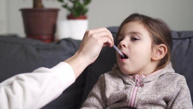 Portrait of caucasian preschool girl taking vitamins with drops at home. Immunity buster concept 