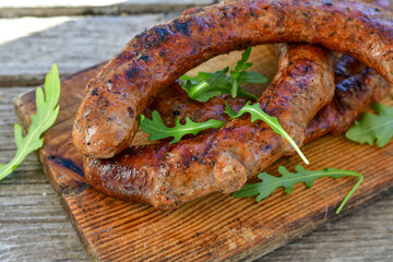 Grilled  pork  juicy sausages on wooden board outdoors. Grilling food, bbq, barbecue, picnic