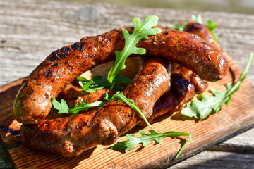 Grilled  pork  juicy sausages on wooden board outdoors. Grilling food, bbq, barbecue, picnic