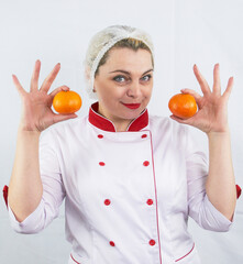 Beautiful ukraine woman in cook clothes holds orange on white background