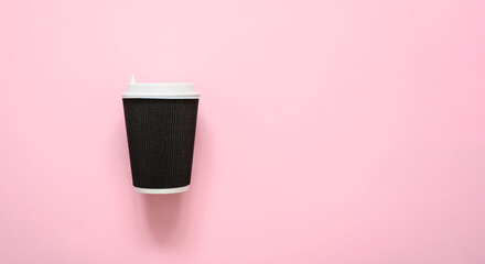 Paper corrugated dark brown cup for coffee on a pink background. copyspace.