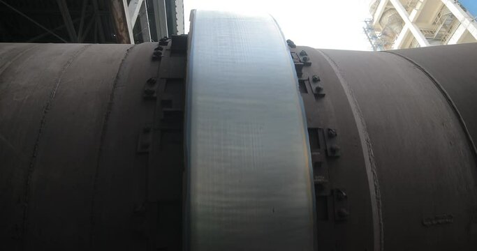 Metal tube is spinning in the factory. Iron flapper in tube is circling. Silver valve in pipe on the factory.