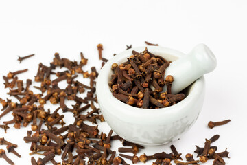 Cloves in white mortar with pestle isolated on white background. Herbal cloves have a fragrant and spicy flavor.