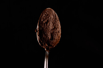 Spoon with melted chocolate on a dark background