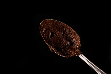 Spoon with melted chocolate on a dark background