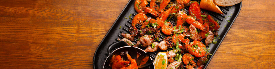 Top view photo of big pan with grilled sea food, mussels shrimps and others.