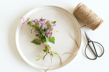 Closeup of Lamium amplexicaule, commonly known as common henbit, or greater henbit, earthenware plate on white table background. Floral composition, feminine styled stock image. A place for your text.