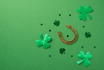 Top view photo of the bronze horseshoe and many confetti different size in shape of clovers and...